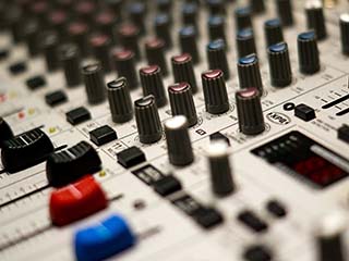Closeup photo of slides and dials on an audio mixing console. Closeup photo of slides and dials on an audio mixing console.