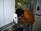 A student kneels by the whiteboard and looks through a hole in a piece of paper taped to the side.